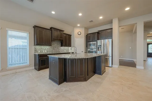 a metallic refrigerator freezer sitting in a kitchen