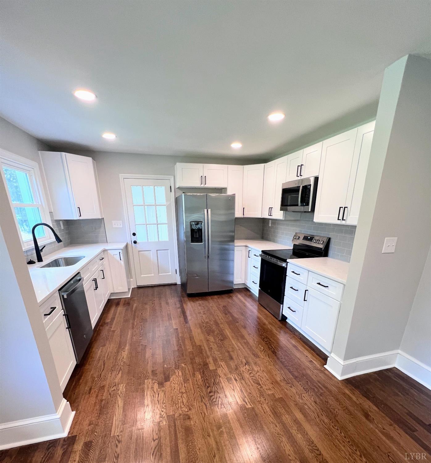 198 Woodbridge Lane Spout Spring, VA 24593 - Photo 6 of 27 a large kitchen with a white stove top oven a refrigerator a sink dishwasher with a fireplace and wooden floor