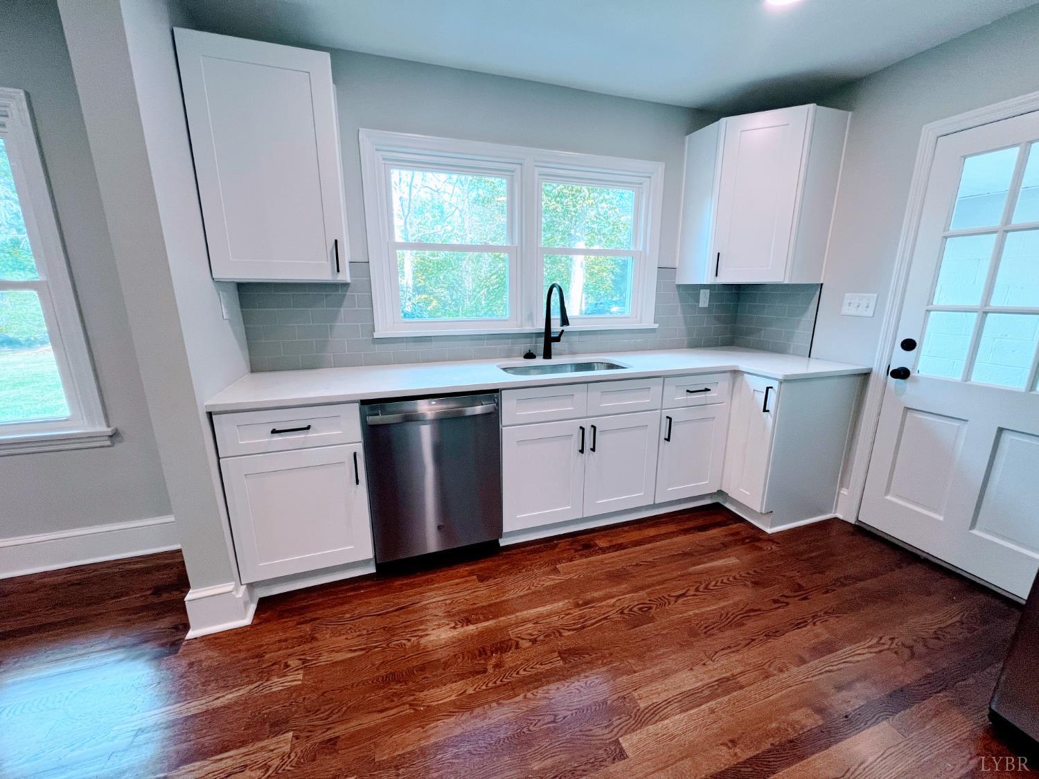 198 Woodbridge Lane Spout Spring, VA 24593 - Photo 7 of 27 a kitchen with wooden floors white cabinets a sink and a window
