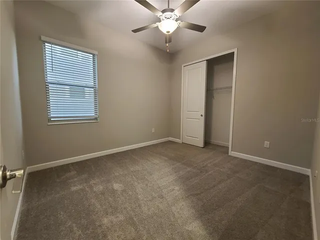 an empty room with fan and windows