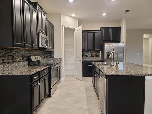 a kitchen with stainless steel appliances granite countertop a sink a stove and a refrigerator