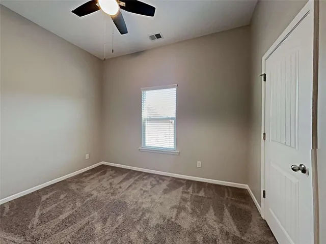 an empty room with a ceiling fan and carpet