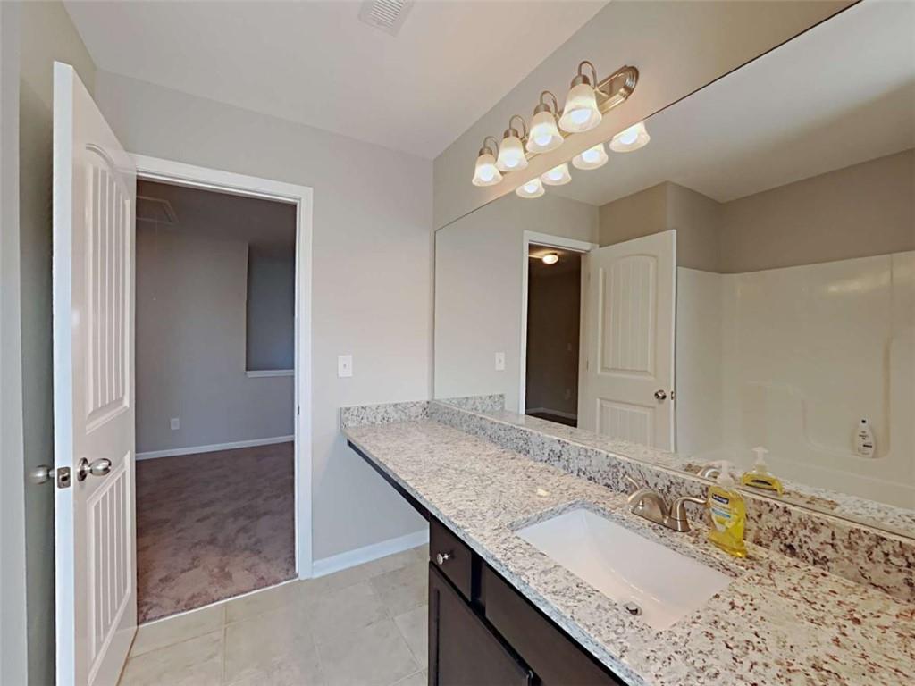 421 Reinhardt Lane Ball Ground, GA 30107 - Photo 21 of 22 a bathroom with a granite countertop sink a large mirror and a vanity