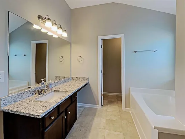 a bathroom with a granite countertop sink a large mirror and a bathtub