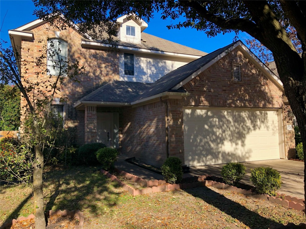 View of front of property with brick siding, a garage, and driveway