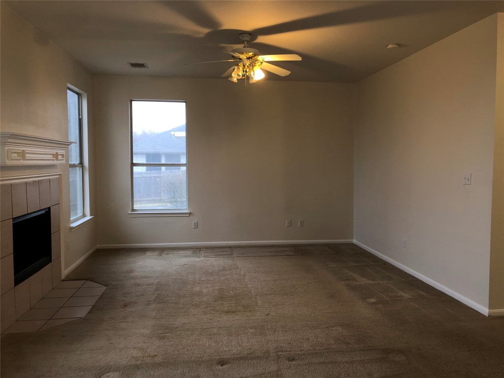 3604 Roller Crossing Austin, TX 78728 - Photo 18 of 40 Unfurnished living room featuring a tile fireplace, ceiling fan, and carpet flooring