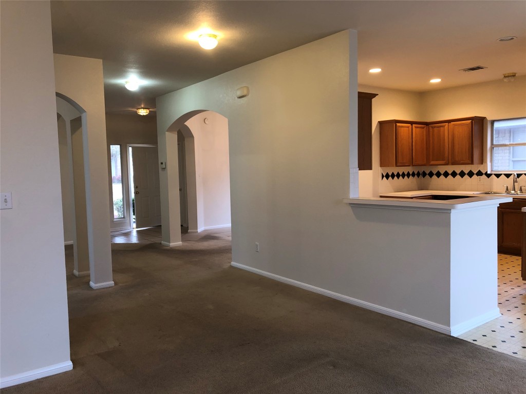 3604 Roller Crossing Austin, TX 78728 - Photo 20 of 40 Kitchen with tasteful backsplash, light countertops, light carpet, brown cabinetry, and a peninsula