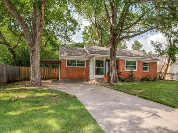 a front view of a house with a garden and trees