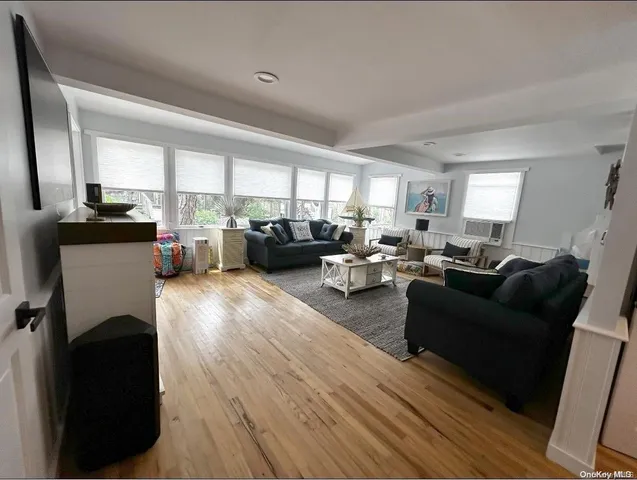 a living room with furniture kitchen view and a wooden floor