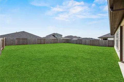 a view of yard with grass and wooden fence