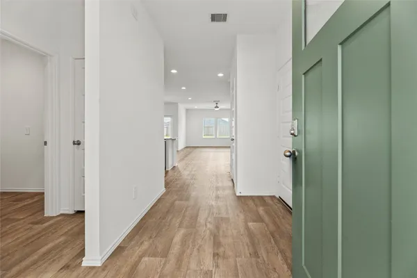 a view of a hallway with wooden floor and a bathroom
