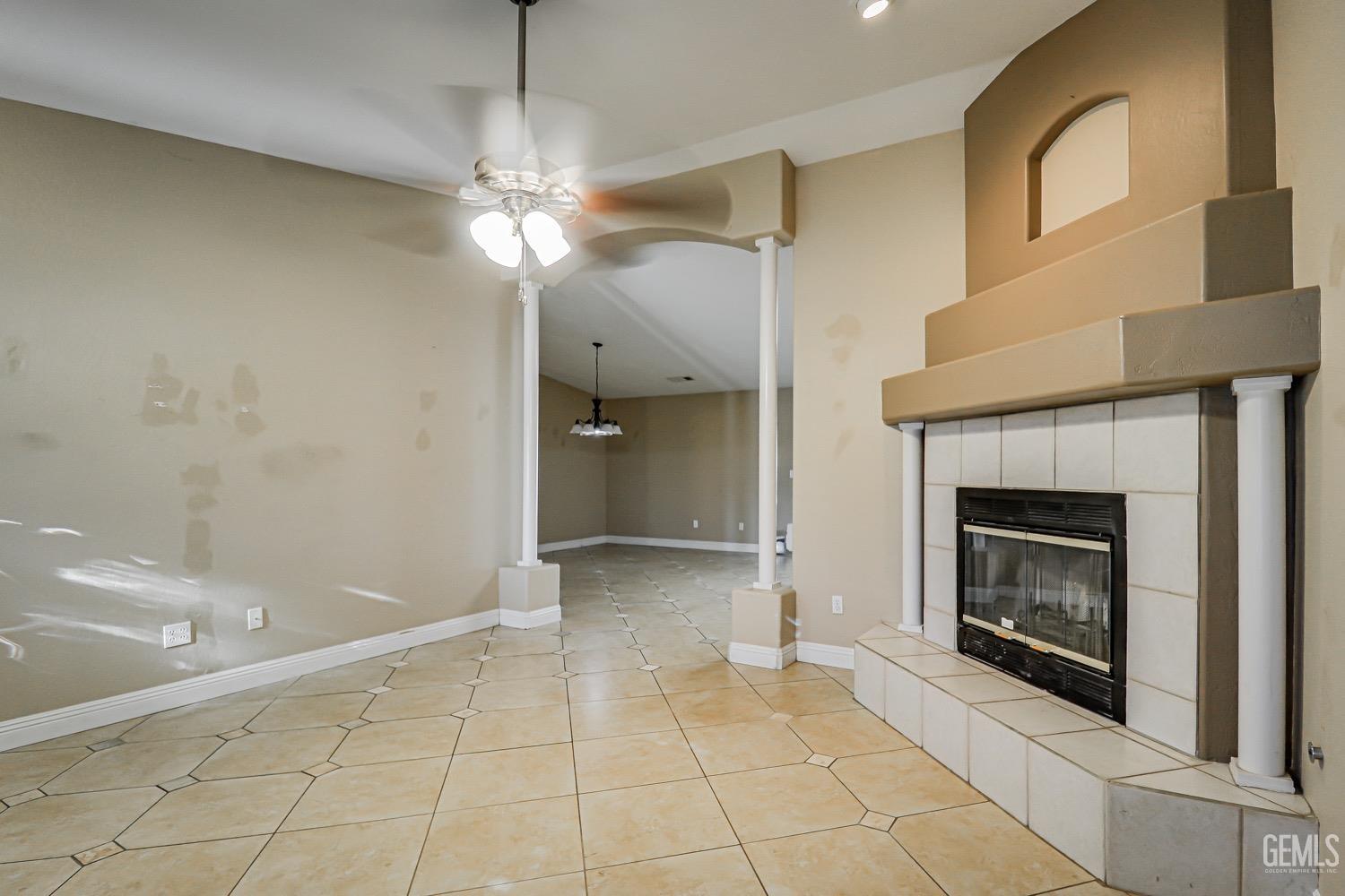 Undisclosed Address Bakersfield, CA 93312 - Photo 6 of 28 a view of an empty room with a fireplace and a chandelier fan