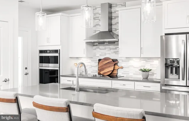 a kitchen with stainless steel appliances a refrigerator a stove a sink and white cabinets with wooden floor