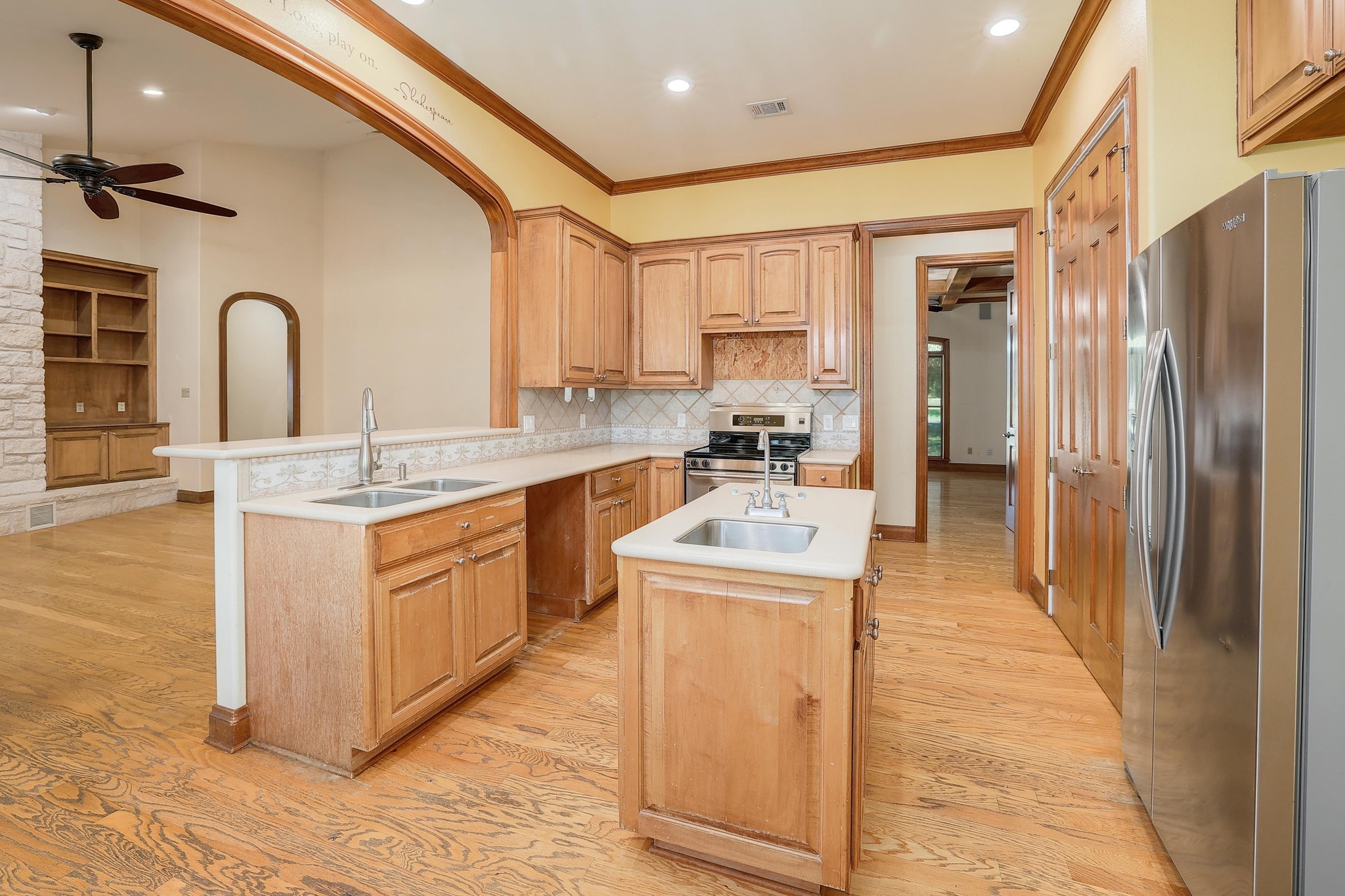 3900 Shell Road Georgetown, TX 78628 - Photo 11 of 40 Kitchen with appliances with stainless steel finishes, light wood finished floors, arched walkways, a peninsula, and an island with sink
