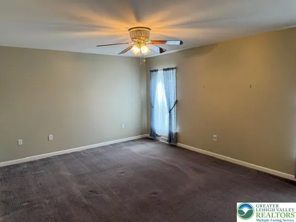 an empty room with a chandelier fan and windows