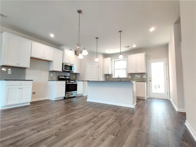 a kitchen with stainless steel appliances granite countertop a sink a stove and a wooden floors