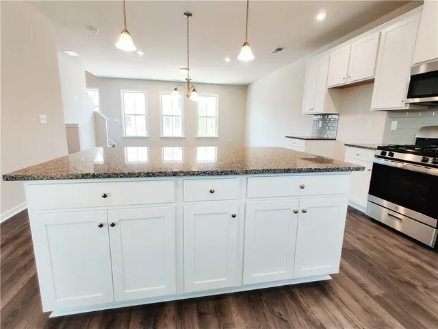 a kitchen with granite countertop a stove and a microwave