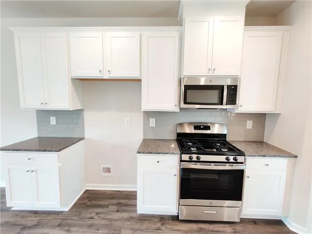 a kitchen with granite countertop white cabinets and a sink