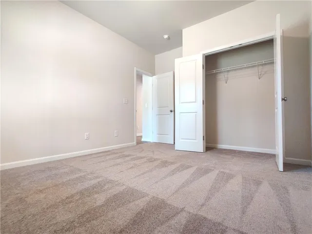 a view of an empty room with closet and a window