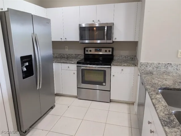 a kitchen with granite countertop a stove a microwave and refrigerator