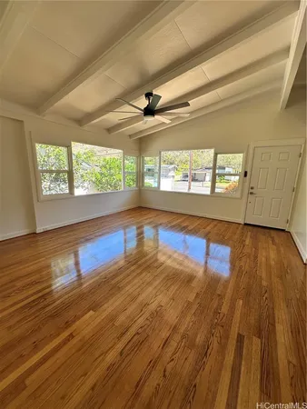 a view of empty room with wooden floor and fan