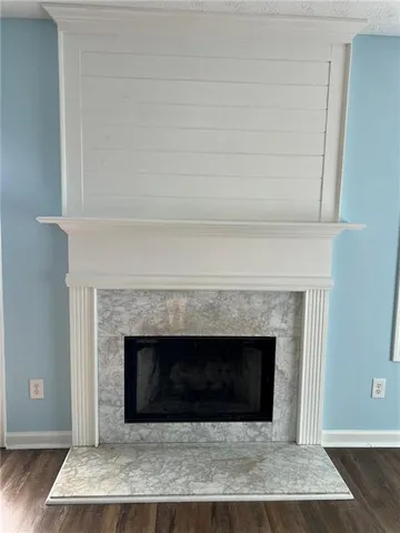 an empty room with wooden floor fireplace and windows