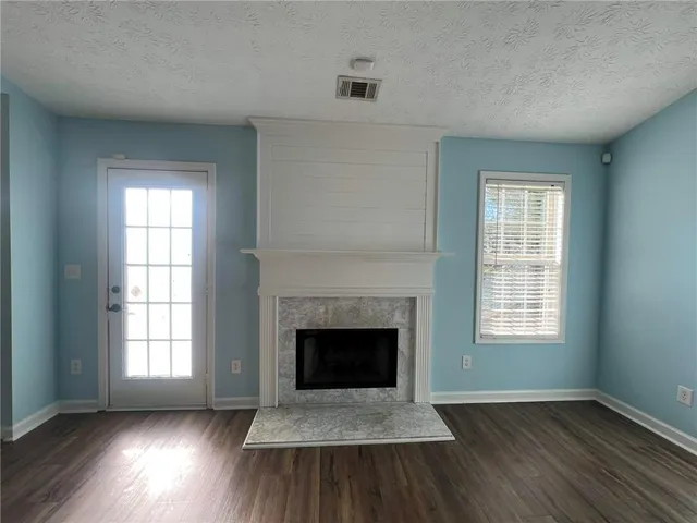 an empty room with wooden floor chandelier fan and windows