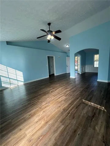 a view of an empty room with window and wooden floor