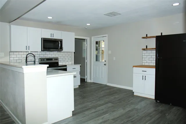 a room with kitchen island a sink and wooden floor