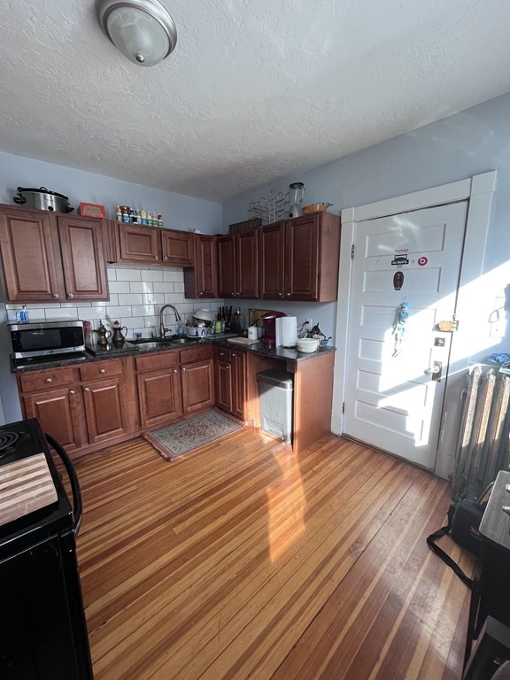 23 Sumner Terrace Springfield, MA 01108 - Photo 16 of 24 a large kitchen with stainless steel appliances granite countertop a stove top oven a sink dishwasher and wooden cabinets with wooden floor