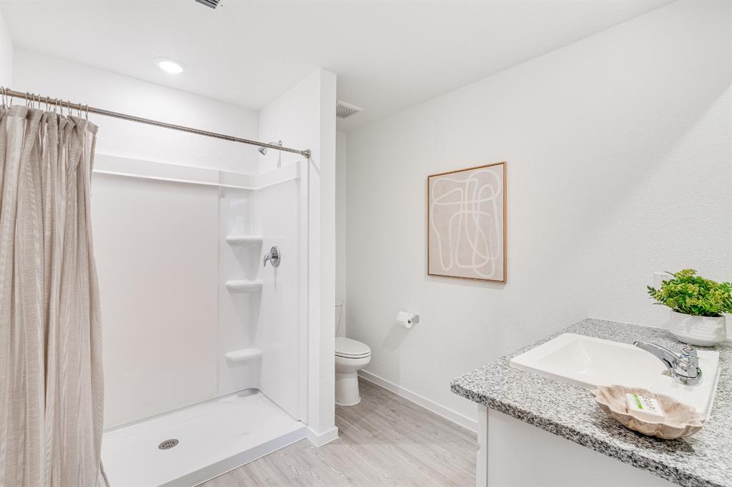 1287 Maple Street Wilmer, TX 75172 - Photo 15 of 22 a bathroom with a granite countertop sink a toilet and shower
