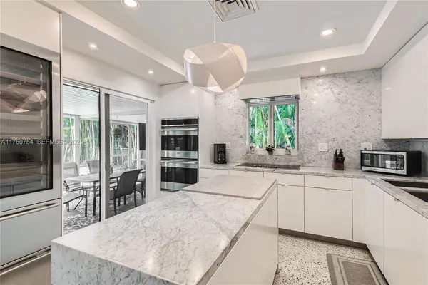 a kitchen with stainless steel appliances a sink a stove a refrigerator cabinets and a dining table with wooden floor