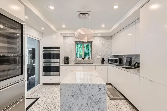 a large kitchen with stainless steel appliances kitchen island granite countertop a refrigerator and a stove top oven