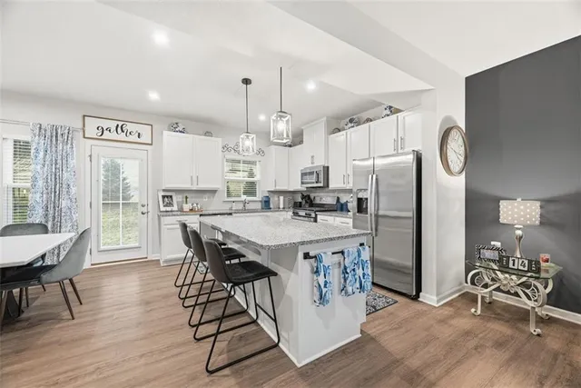 a kitchen with stainless steel appliances granite countertop a table chairs stove and refrigerator