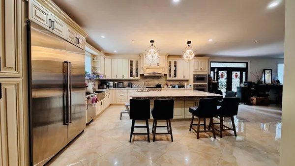 a kitchen with stainless steel appliances kitchen island granite countertop a table chairs sink and cabinets