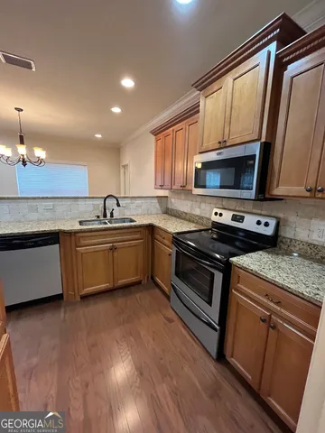 a kitchen with stainless steel appliances a sink a stove a microwave a refrigerator a window