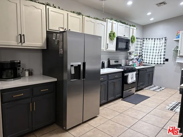 a kitchen with stainless steel appliances a sink a stove a refrigerator cabinets and a window