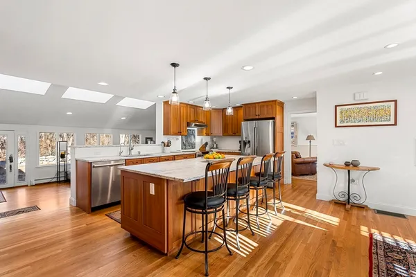a kitchen with stainless steel appliances granite countertop a table chairs and a refrigerator
