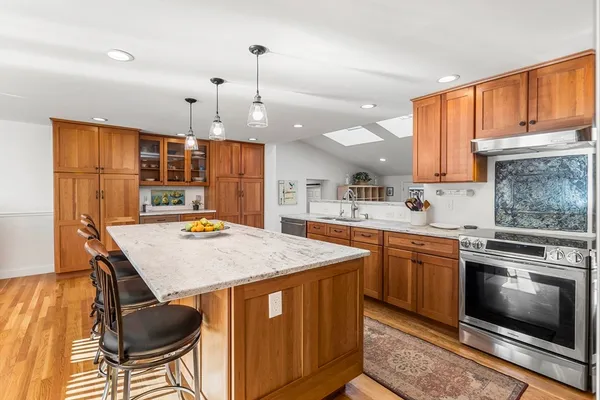 a kitchen with stainless steel appliances granite countertop a sink a stove a refrigerator cabinets and chairs