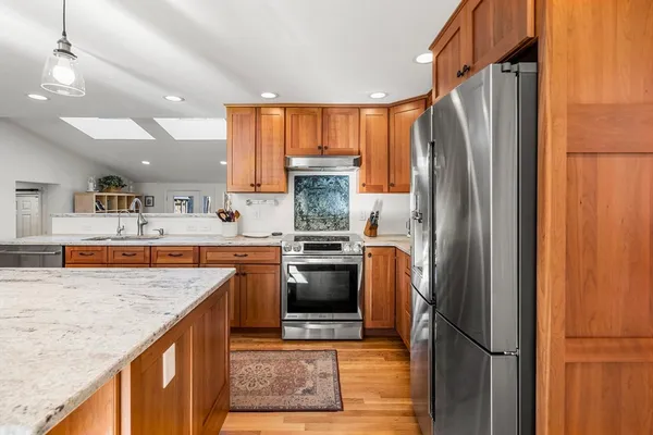 a kitchen with stainless steel appliances granite countertop a refrigerator a sink and a stove
