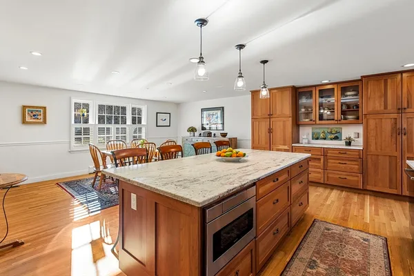 a large kitchen with kitchen island a stove a refrigerator a sink dishwasher with a dining table and chairs with wooden floor