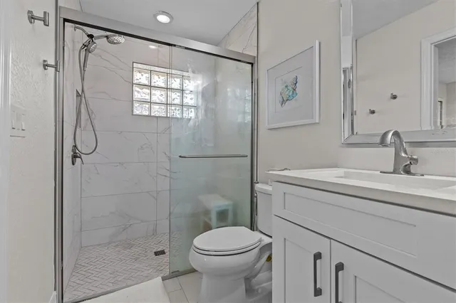 a bathroom with a shower sink vanity mirror and toilet