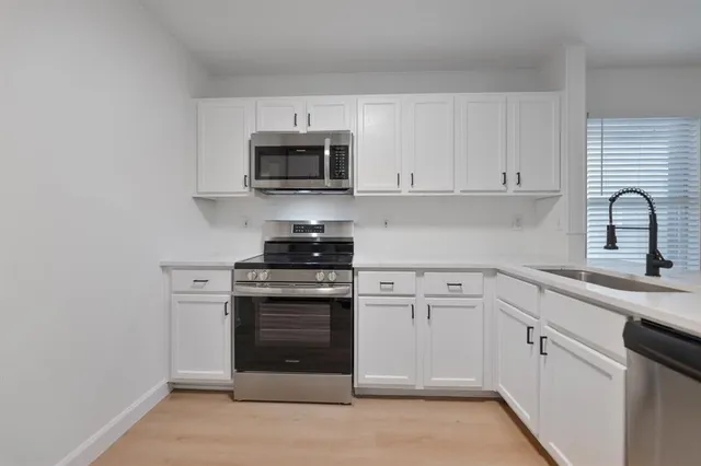 a kitchen with white cabinets stainless steel appliances and sink