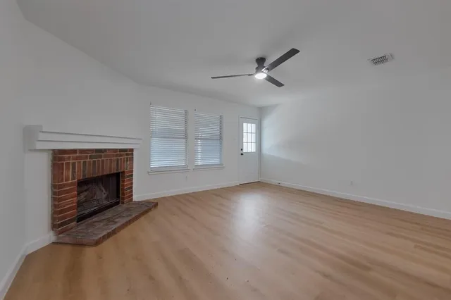 a view of empty room with wooden floor fireplace and window