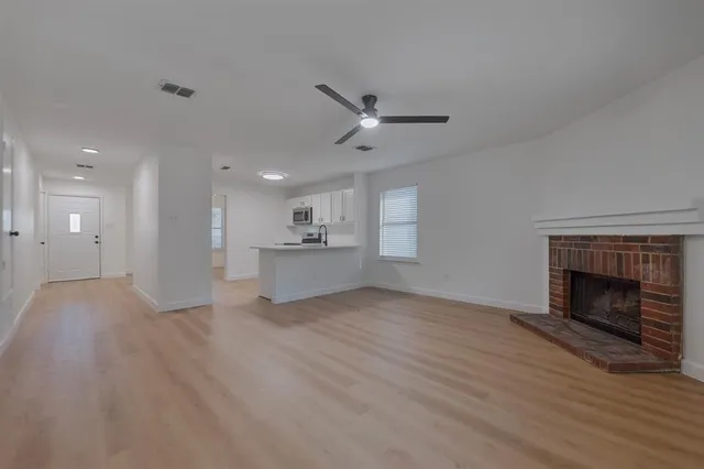 a view of an empty room with wooden floor and a fireplace