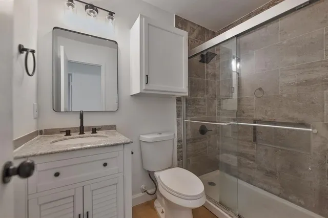 a bathroom with a granite countertop sink toilet and shower
