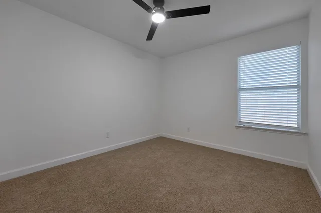 an empty room with a window and a ceiling fan