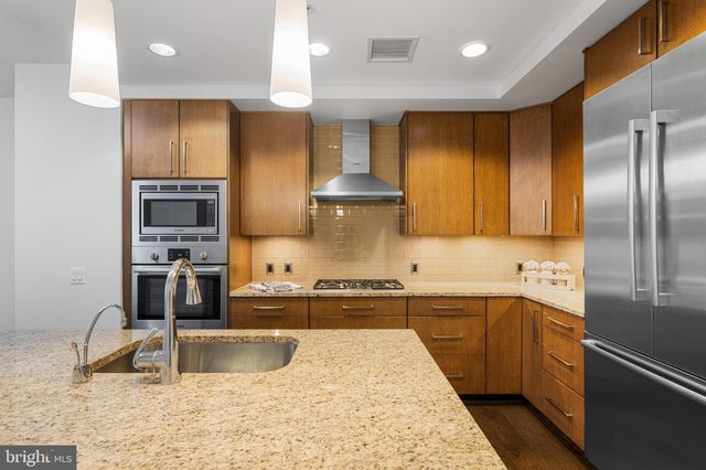 a kitchen with stainless steel appliances granite countertop a sink and a refrigerator