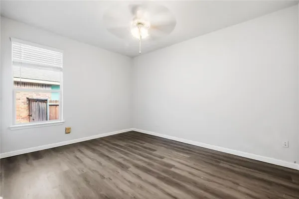 an empty room with wooden floor and a ceiling fan
