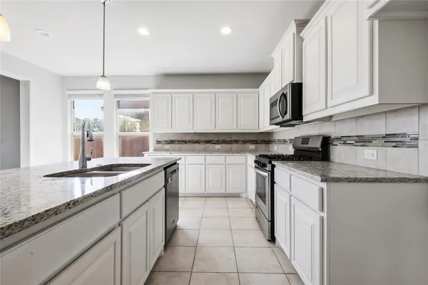 a kitchen with stainless steel appliances granite countertop a sink and dishwasher a stove top oven with white cabinets